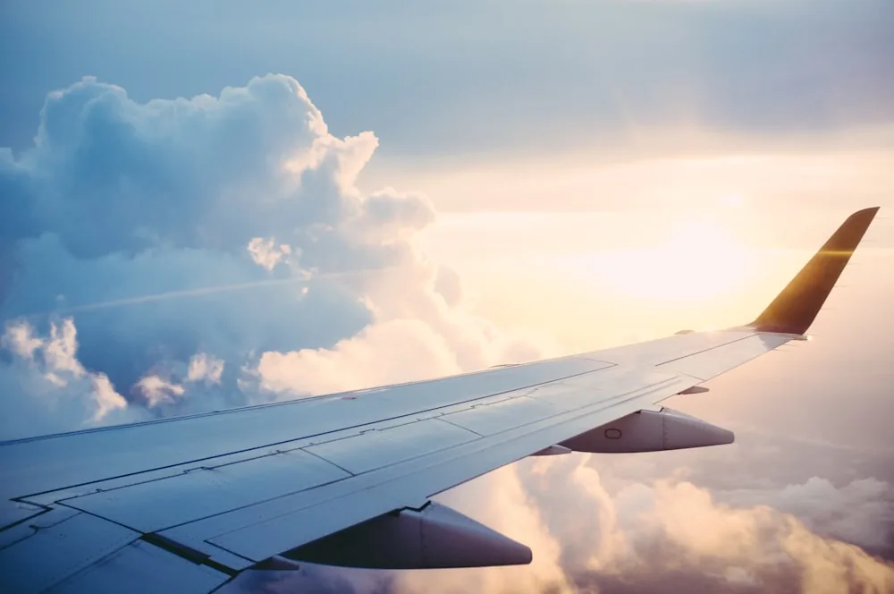 Airplane wing over clouds during international travel